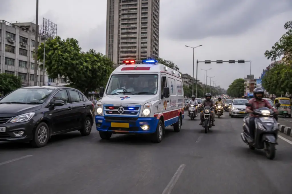 Gujarat 108 emergency service ambulance responding on a busy Indian road