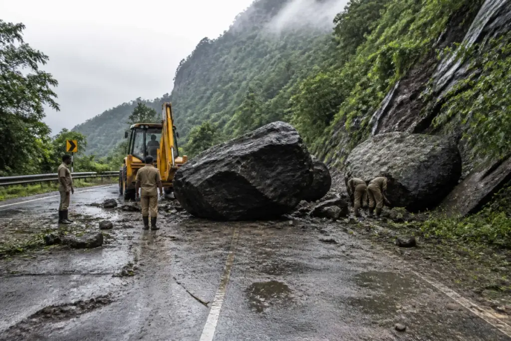 Valparai landslide blocking a rain-soaked ghat road with large boulders near a hairpin bend