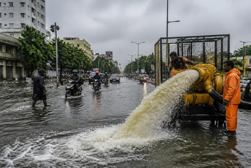 Chennai rainfall causes waterlogging on an urban street as civic workers operate pumps.