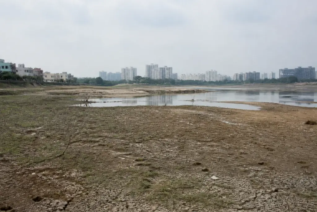Telangana rainfall deficit leaves a dry urban water body under an overcast Hyderabad sky.