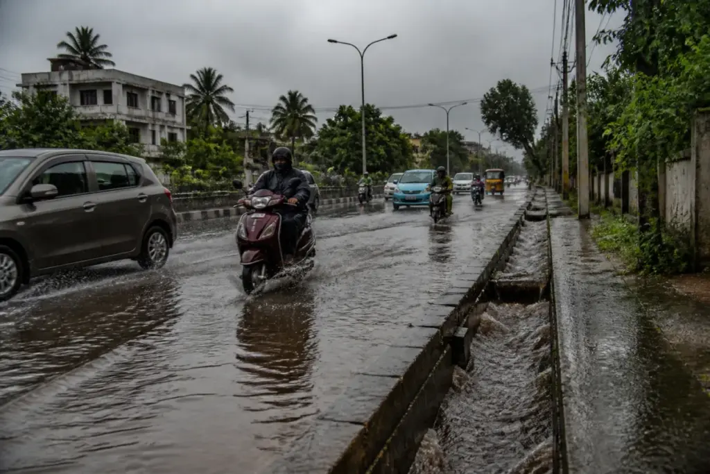 Tamil Nadu rainfall over a rain-soaked urban road with vehicles and drainage channels