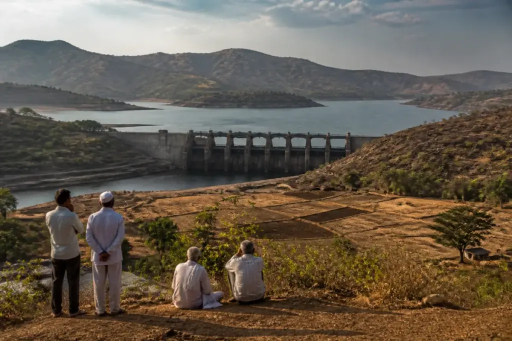 Dimbhe Dam water storage behind the reservoir, with dry farmland and hills in Pune district